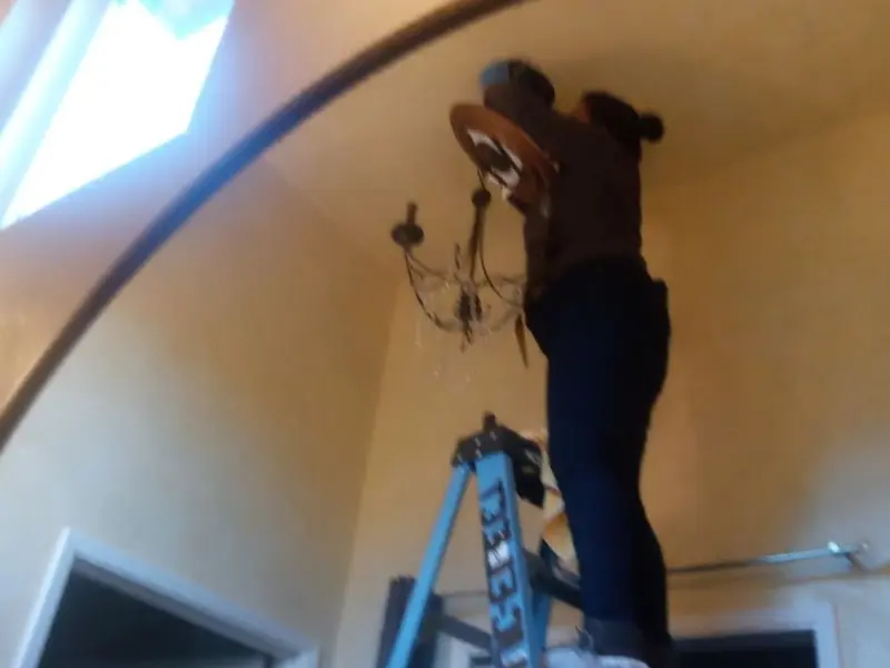 Electrician installing a chandelier in a Southeast Arcadia residence